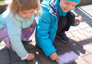 Julka i Jaś rysują kredą na chodniku